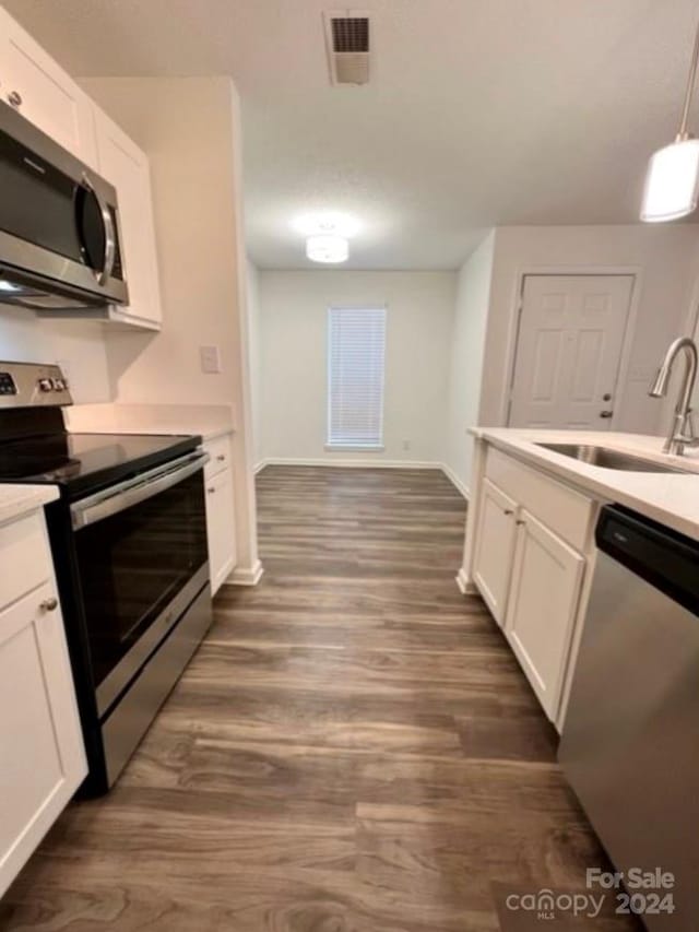 kitchen with hanging light fixtures, dark hardwood / wood-style flooring, white cabinetry, sink, and stainless steel appliances