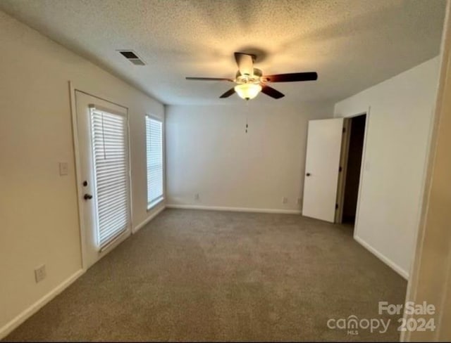 spare room with dark colored carpet, a textured ceiling, and ceiling fan