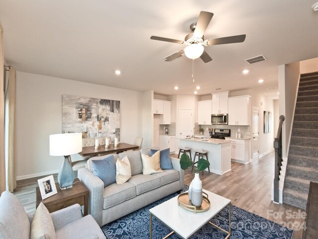 living room featuring ceiling fan, sink, and light hardwood / wood-style flooring