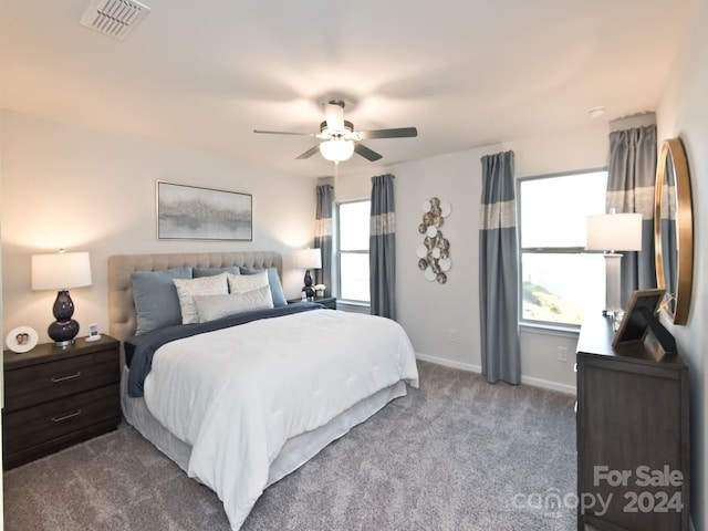 carpeted bedroom featuring multiple windows and ceiling fan