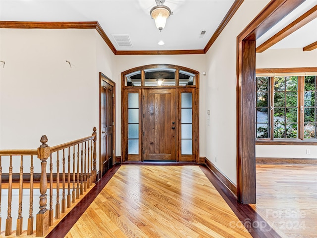 foyer entrance with hardwood / wood-style floors and crown molding