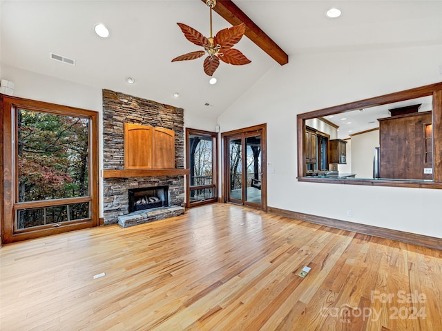 unfurnished living room featuring light wood-type flooring, plenty of natural light, beamed ceiling, and ceiling fan