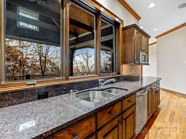 kitchen featuring crown molding, stainless steel appliances, sink, light hardwood / wood-style floors, and dark stone countertops