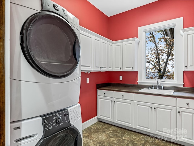 washroom with cabinets, stacked washer and clothes dryer, and sink