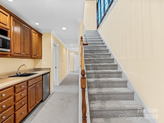 stairs with sink, carpet flooring, and crown molding