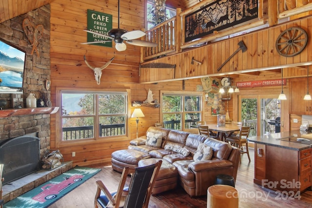 living room with a stone fireplace, wood walls, plenty of natural light, and dark hardwood / wood-style floors