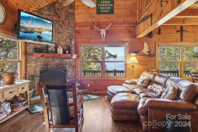 living room featuring a wealth of natural light, wooden walls, vaulted ceiling, and hardwood / wood-style flooring