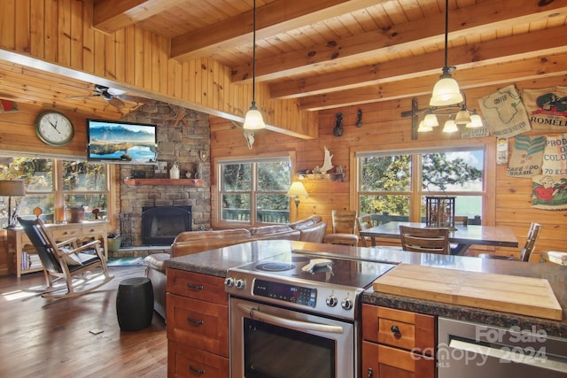 kitchen featuring high end stove, wooden walls, a fireplace, and decorative light fixtures