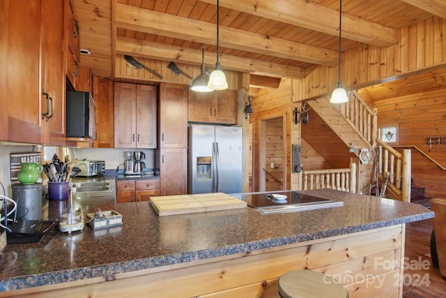 kitchen with beam ceiling, stainless steel appliances, wooden walls, and hanging light fixtures