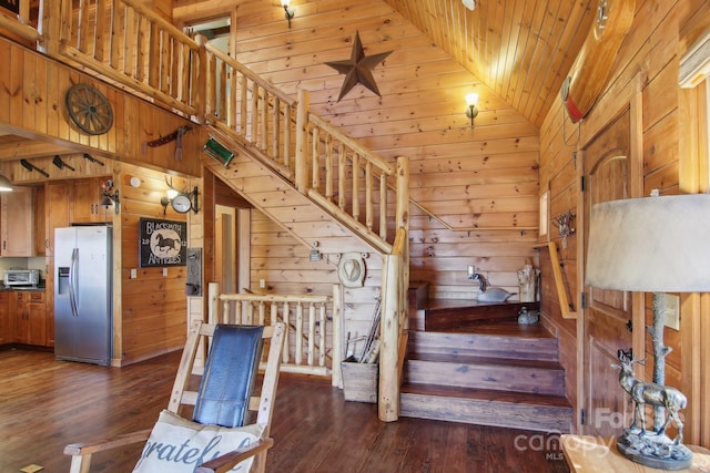 stairway with high vaulted ceiling, hardwood / wood-style floors, wooden walls, and wooden ceiling