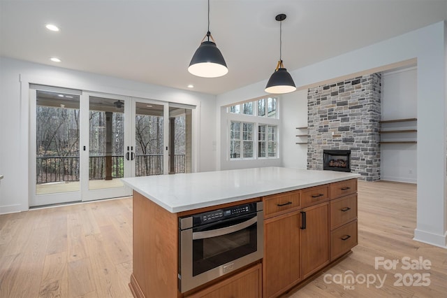 6630 Vesuvius Furnace Rd Unit 1, Denver, NC 28037 - kitchen featuring wall oven, a center island, light countertops, light wood-style flooring, and hanging light fixtures