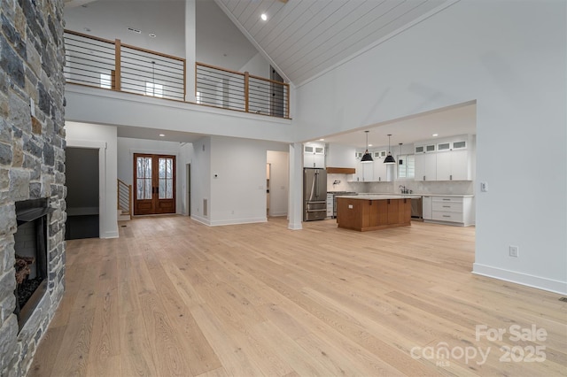 6630 Vesuvius Furnace Rd Unit 1, Denver, NC 28037 - unfurnished living room with baseboards, a high ceiling, a fireplace, light wood-style floors, and french doors