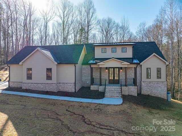 view of front of house featuring brick siding, roof with shingles, french doors, metal roof, and a standing seam roof