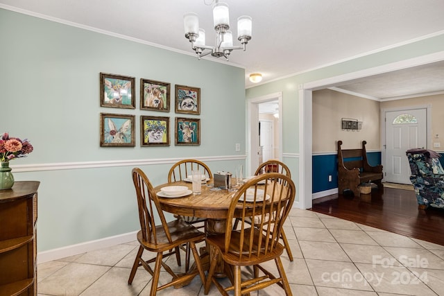 dining space with crown molding, light hardwood / wood-style floors, and an inviting chandelier