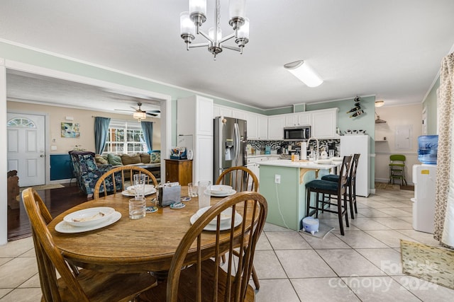 tiled dining room featuring ceiling fan with notable chandelier and ornamental molding