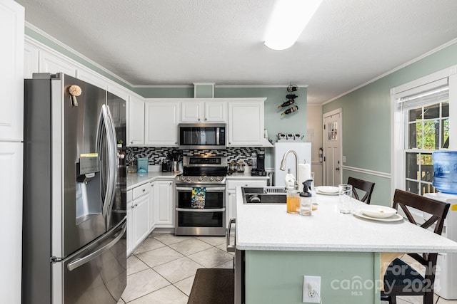 kitchen featuring appliances with stainless steel finishes, a kitchen breakfast bar, light tile patterned floors, white cabinetry, and an island with sink