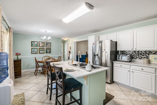 kitchen with white cabinets, stainless steel fridge, and a center island with sink