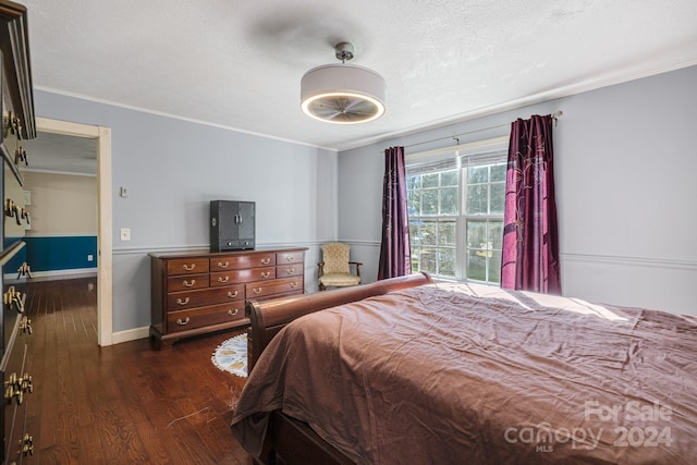 bedroom with a textured ceiling, dark hardwood / wood-style floors, and ornamental molding