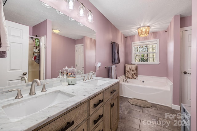 bathroom with tile patterned flooring, a bathtub, a textured ceiling, and vanity