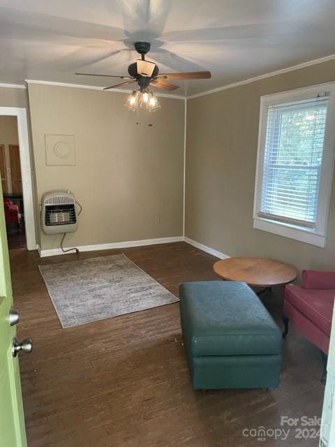 living area featuring crown molding, heating unit, dark hardwood / wood-style floors, and ceiling fan