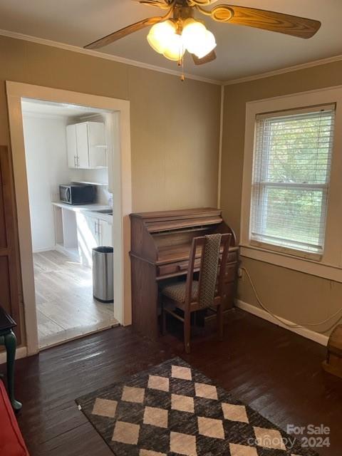 unfurnished office featuring ornamental molding, dark wood-type flooring, and ceiling fan