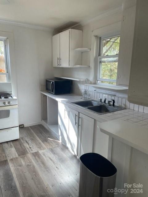 kitchen featuring white cabinets, white gas stove, light wood-type flooring, crown molding, and sink