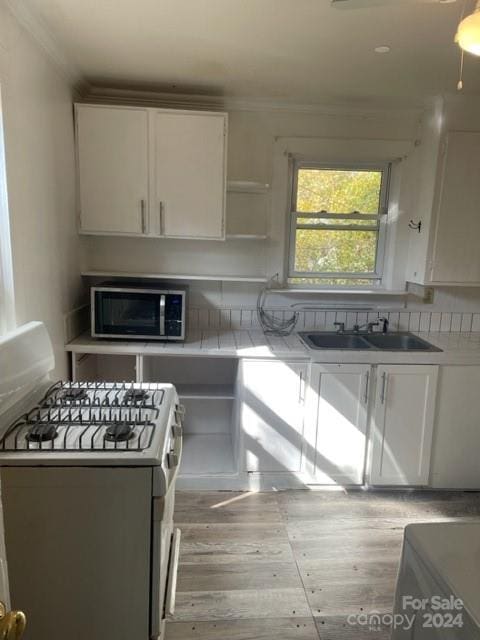 kitchen featuring white cabinets, white gas range, and sink