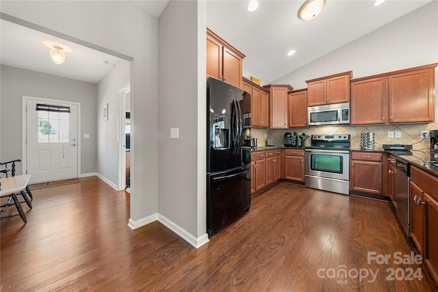 kitchen with decorative backsplash, appliances with stainless steel finishes, vaulted ceiling, and dark hardwood / wood-style floors