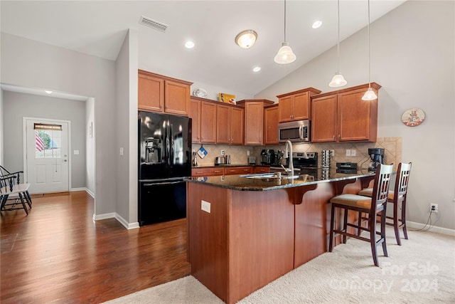 kitchen featuring tasteful backsplash, black refrigerator with ice dispenser, hanging light fixtures, dark wood-type flooring, and dark stone countertops