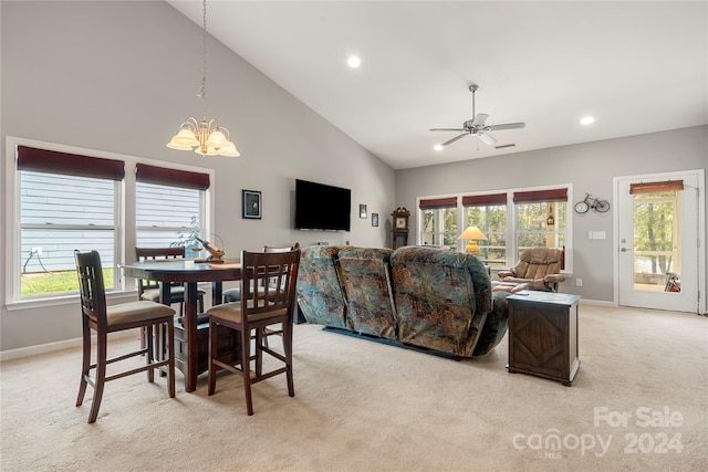 dining room with ceiling fan with notable chandelier, high vaulted ceiling, and light colored carpet