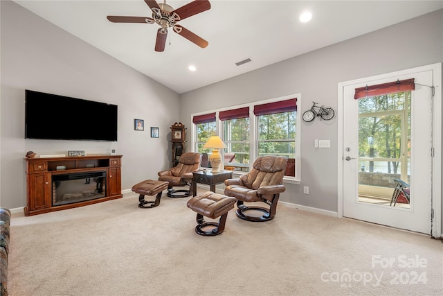 living area featuring lofted ceiling, light colored carpet, and ceiling fan