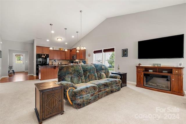 carpeted living room featuring a notable chandelier, high vaulted ceiling, and plenty of natural light