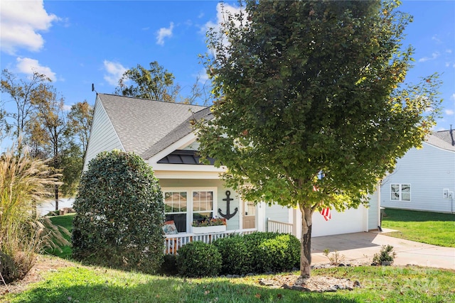 view of property hidden behind natural elements featuring a front lawn and a garage