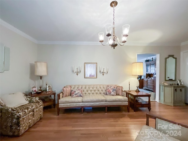 living room with wood-type flooring, a notable chandelier, and ornamental molding