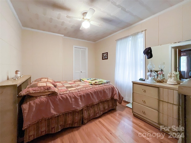 bedroom featuring light hardwood / wood-style flooring, ceiling fan, crown molding, and a closet