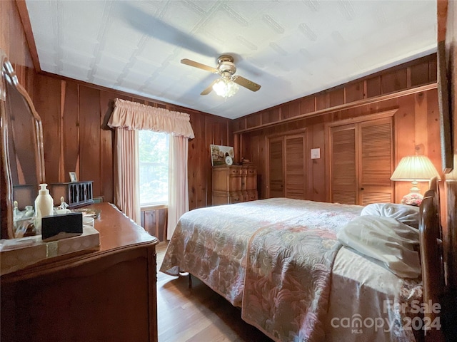 bedroom featuring wood walls, ceiling fan, and hardwood / wood-style floors