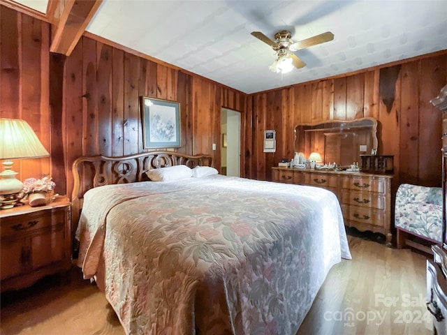 bedroom with light hardwood / wood-style floors, wood walls, and ceiling fan