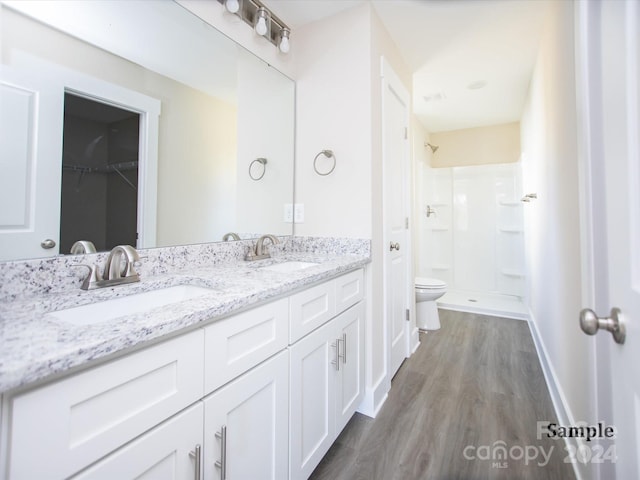 bathroom with a shower, vanity, hardwood / wood-style flooring, and toilet