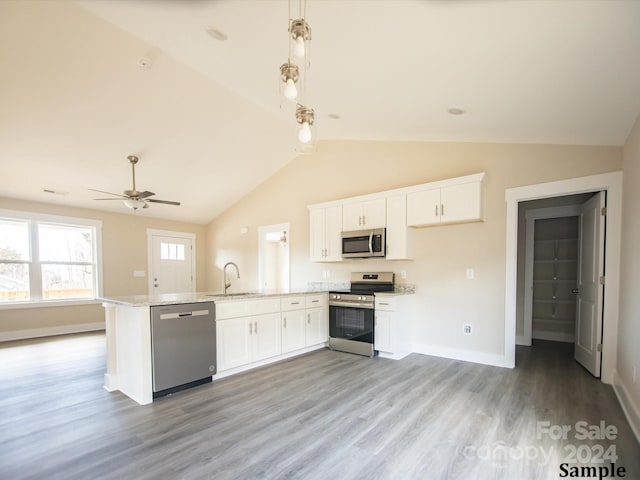 kitchen featuring hanging light fixtures, appliances with stainless steel finishes, lofted ceiling, white cabinets, and light wood-type flooring