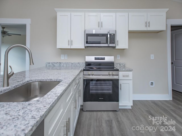 kitchen featuring white cabinetry, sink, ceiling fan, stainless steel appliances, and light hardwood / wood-style flooring