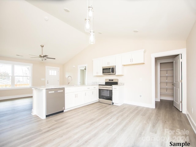 kitchen featuring pendant lighting, lofted ceiling, white cabinets, light wood-type flooring, and appliances with stainless steel finishes