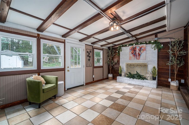 unfurnished sunroom featuring a brick fireplace and beam ceiling