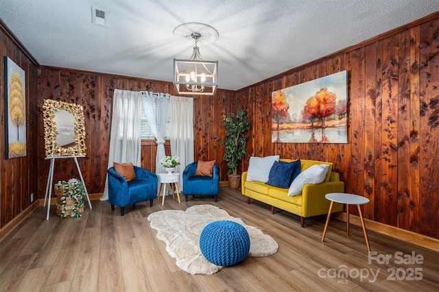 sitting room featuring a textured ceiling, wood finished floors, visible vents, and crown molding