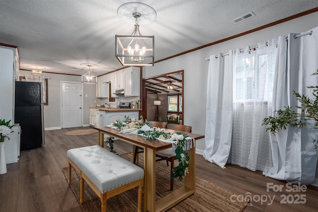 dining room with dark wood-style flooring, crown molding, a notable chandelier, visible vents, and a textured ceiling