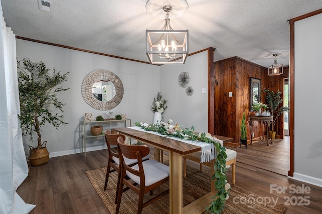 dining space featuring dark wood-style floors, visible vents, a textured ceiling, and ornamental molding