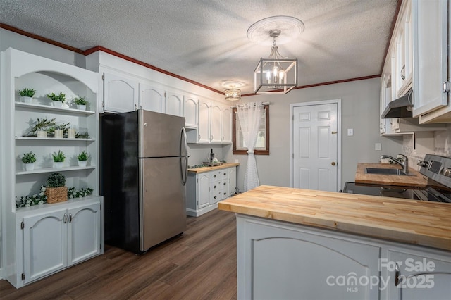 kitchen featuring hanging light fixtures, wooden counters, freestanding refrigerator, and white cabinetry