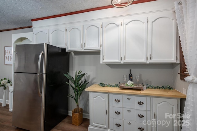 kitchen featuring butcher block counters, white cabinetry, and freestanding refrigerator