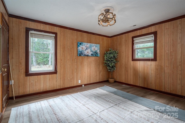 empty room with baseboards, a wealth of natural light, and wood finished floors