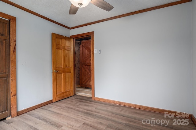 empty room featuring ornamental molding, baseboards, light wood-style flooring, and a textured ceiling