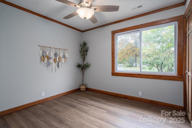 spare room with a wealth of natural light, light wood finished floors, and visible vents